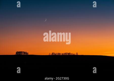 Der fast 2 Tage alte und sehr dünne, sich wachend verwachsenden Mond und die Venus in der Abenddämmerung. Stockfoto