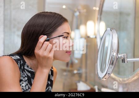 Frau immer bereit für die Arbeit tun Morgen Make-up Routine Putting Mascara in Badezimmerspiegel zu Hause. Schöne asiatische Geschäftsfrau Anwendung Auge machen Stockfoto