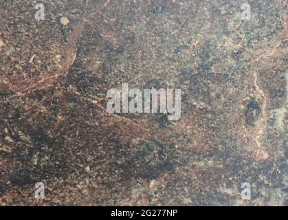 Eine flache Oberfläche aus natürlichem dunklem Stein mit braunen Flecken und kleinen Schlaglöchern aus der Nähe. Hintergrund, Muster, Textur. Stockfoto
