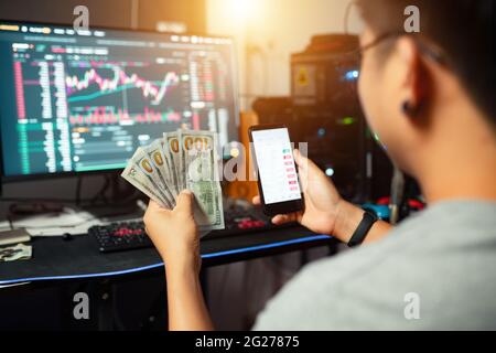 Ein junger Trader, der einen USD-Trading-Geldwechsel mit Krypto-Blockchain online hält Stockfoto