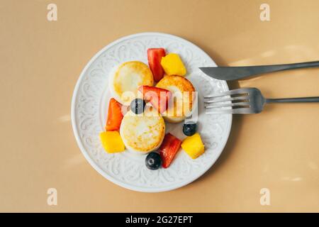 Frühstücksangebot. Hüttenkäse-Pfannkuchen auf dem Teller. Syrniki mit Beere, Draufsicht. Stockfoto