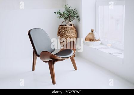 Moderner Sessel aus schwarzem Leder und Holz in einem weißen Loft-Interieur. Designer-Stuhl. Weicher, selektiver Fokus. Stockfoto