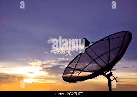 Eine schwarze Satellitenschüssel auf dem Hintergrund des Dämmerungshimmels Stockfoto