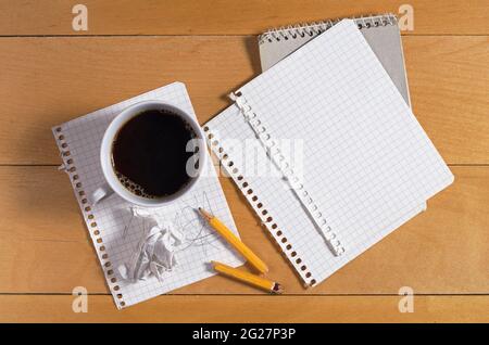 Leeres Notizbuch, gebrochener Bleistift und zerknittertes Papier auf einem Holztisch mit einer Tasse Kaffee, Draufsicht Stockfoto