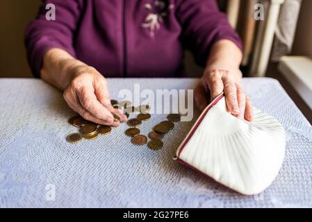 Besorgte ältere Frau, die zu Hause sitzt und die verbleibenden Münzen zählt.alt Frau, die zu Hause kläglich am Tisch sitzt und zählt Verbleibende Münzen für Stockfoto