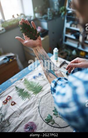 Junger Mann, der eine Pflanze mit getrockneten grünen Blättern hält Stockfoto