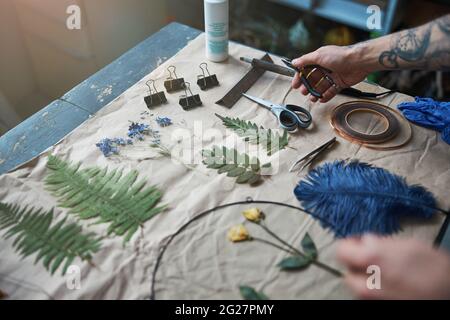 Junger Mann mit Zangen und Herbarium in der Werkstatt Stockfoto