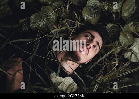 Junger Mann im Wald liegt auf nassem Gras und träumt beim Denken Stockfoto