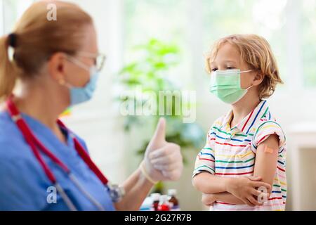 Kind in der Arztklinik nach Covid-19-Impfung. Kind mit Verband an seinem Arm nach dem Coronavirus-Impfstoff. Schutz vor Immunität und Virusverbreitung. Stockfoto