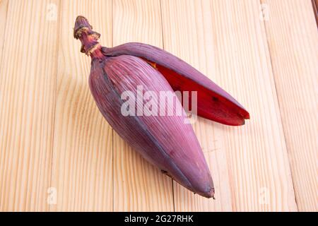 Frische Bananenblüte oder Bananenblüte, essbares Gemüse, das hauptsächlich in Südostasien verwendet wird, auf einem Holztisch mit Struktur angeordnet Stockfoto