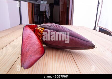 Frische Bananenblüte oder Bananenblüte, essbares Gemüse, das hauptsächlich in Südostasien verwendet wird, auf einem Holztisch mit Struktur angeordnet Stockfoto