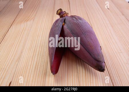 Frische Bananenblüte oder Bananenblüte, essbares Gemüse, das hauptsächlich in Südostasien verwendet wird, auf einem Holztisch mit Struktur angeordnet Stockfoto