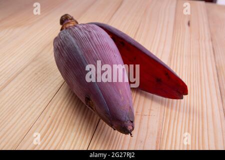 Frische Bananenblüte oder Bananenblüte, essbares Gemüse, das hauptsächlich in Südostasien verwendet wird, auf einem Holztisch mit Struktur angeordnet Stockfoto