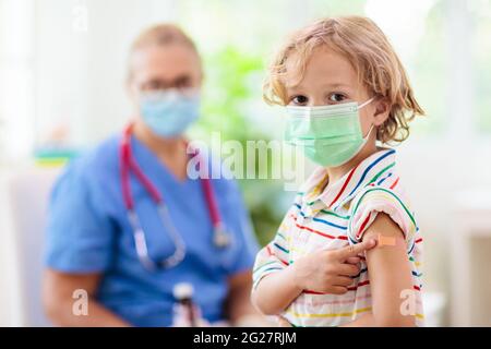 Kind in der Arztklinik nach Covid-19-Impfung. Kind mit Verband an seinem Arm nach dem Coronavirus-Impfstoff. Schutz vor Immunität und Virusverbreitung. Stockfoto