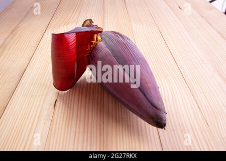 Frische Bananenblüte oder Bananenblüte, essbares Gemüse, das hauptsächlich in Südostasien verwendet wird, auf einem Holztisch mit Struktur angeordnet Stockfoto
