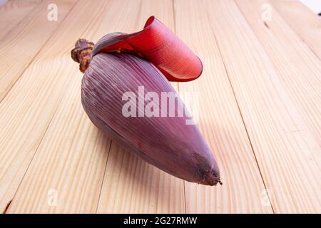 Frische Bananenblüte oder Bananenblüte, essbares Gemüse, das hauptsächlich in Südostasien verwendet wird, auf einem Holztisch mit Struktur angeordnet Stockfoto