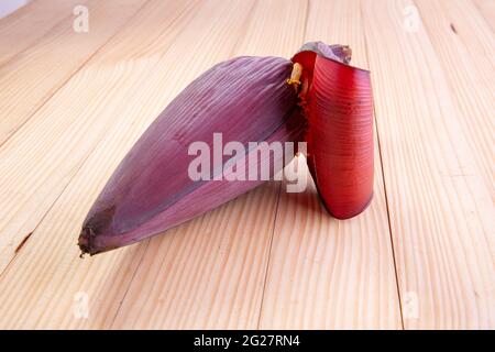 Frische Bananenblüte oder Bananenblüte, essbares Gemüse, das hauptsächlich in Südostasien verwendet wird, auf einem Holztisch mit Struktur angeordnet Stockfoto
