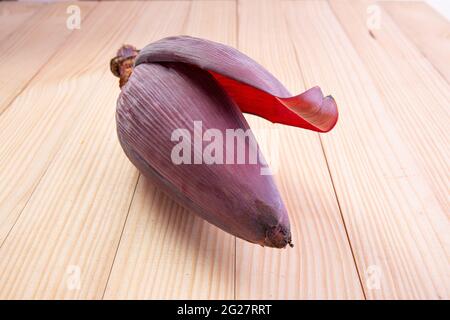 Frische Bananenblüte oder Bananenblüte, essbares Gemüse, das hauptsächlich in Südostasien verwendet wird, auf einem Holztisch mit Struktur angeordnet Stockfoto