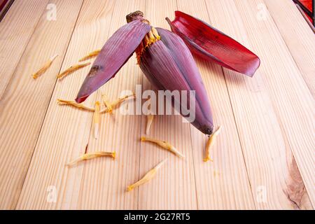 Frische Bananenblüte oder Bananenblüte, essbares Gemüse, das hauptsächlich in Südostasien verwendet wird, auf einem Holztisch mit Struktur angeordnet Stockfoto