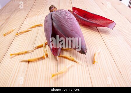 Frische Bananenblüte oder Bananenblüte, essbares Gemüse, das hauptsächlich in Südostasien verwendet wird, auf einem Holztisch mit Struktur angeordnet Stockfoto