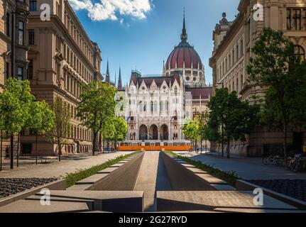 Budapest, Ungarn - das Denkmal der Nationalen Einheit in Alkotmany Straße und Parlament von Ungarn mit traditionellen gelben Straßenbahn an einem sonnigen Sommertag wi Stockfoto