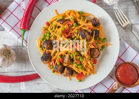Glutenfreies Nudelgericht mit serbischen Cevapcici, Ajvar und Gemüse auf einem Teller Stockfoto