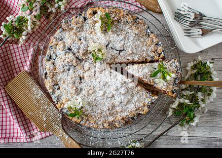 Traditioneller und rustikaler deutscher Kirschkuchen oder Kirschkrümelkuchen, serviert auf einem Kühlregal auf altmodischem Tischhintergrund. Nahaufnahme und abgelegene Sicht Stockfoto