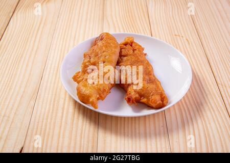 Bananenfritter oder Bananenbraten oder Pazham pori, indischer gebratener Snack, isoliert auf Keramikplatte mit Holzhintergrund. Stockfoto