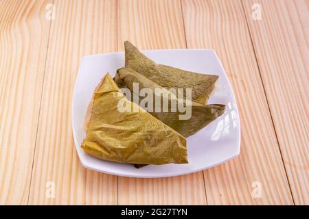 Ela Ada oder gedämpfte süße Reisdumblings, gedämpfte Reiskuchen in Bananenblatt verpackt, Kerala traditionelle Snacks, in einer weißen Keramikplatte angeordnet Stockfoto