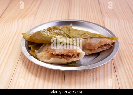 Ela Ada oder gedämpfte süße Reisdumblings, gedämpfte Reiskuchen in Bananenblatt verpackt, Kerala traditionelle Snacks Artikel, in einer Stahlplatte angeordnet. Stockfoto