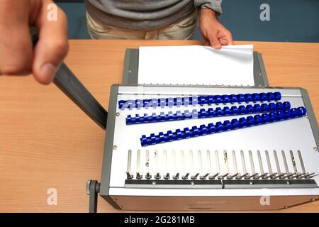 Männlicher Mann, der Seiten am Tisch im Papierladen einband Stockfoto