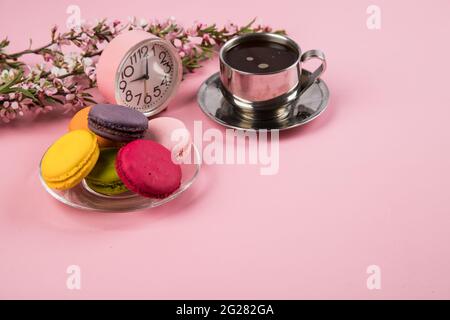 Eine Tasse Kaffee am Morgen mit Makronen-Keksen auf einem rosa Papierhintergrund. Stockfoto