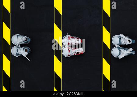Konzept der sozialen Distanzierung. Turnschuhe und Warnband auf dem Asphalt-Hintergrund. Speicherplatz kopieren. Halten Sie Abstand, um die Ausbreitung des Virus zu verhindern. Neu Stockfoto