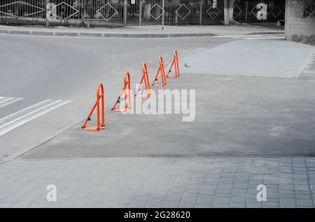 Parkbarrieren in einer Reihe. Fünf orangefarbene Metall-Klappbarrieren auf dem Bürgersteig. Tagsüber. Stockfoto