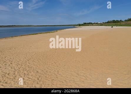 09. Juni 2021, Brandenburg, Großräschen: Der leichte Sand des Stadtstrandes am Großräschener See scheint in der Morgensonne. Der neu geschaffene Strand erinnert an ein wenig karibisches Flair, wenn man ihn betrachtet. Nach Angaben der Lausitzer und Mitteldeutschen Bergbau-Verwaltungsgesellschaft mbH (LMBV) sind Strand und See weiterhin geschlossen. Der Wasserstand im Großräschensee, ehemals Tagebau Meuro, hat seinen endgültigen Wasserstand noch nicht erreicht. Wo einst der Braunkohlenbergbau die Landschaft dominierte, entstehen in ersteren derzeit neue Wasserparadiese mit rund 14,000 Hektar Wasser Stockfoto