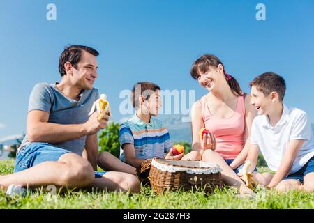 Familie mit zwei Kindern bei einem Picknick mit Früchten im Park im Sommer Stockfoto