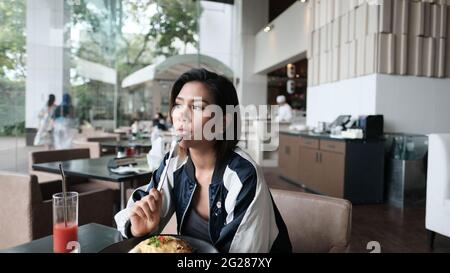 Young Lady beim Essen in einem zwanglosen 5-Sterne-Restaurant, das eine Mahlzeit isst Stockfoto