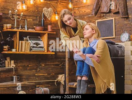 Mädchen liest Buch mit ihrer Mutter, individuelle Bildung Konzept. Mutter überprüft die Hausaufgaben des Kindes. Frau in Wolldecke gewickelt, die mit ihrem Teenager plaudert Stockfoto