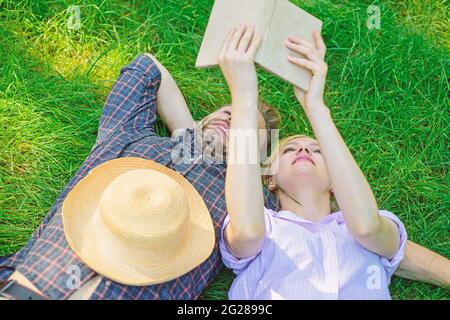 Mann und Mädchen lagen auf Gras und hatten Spaß. Verliebte Paare verbringen ihre Freizeit mit dem Lesen von Büchern. Paar Seelenverwandte bei einem romantischen Date. Romantische paar Studenten genießen Stockfoto