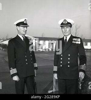 1960er Jahre, historisch, außerhalb der HMS Caledonia, zwei verzierte Royal Naval Captains in voller Uniform für eine Fotografie in einer Übergabe des Kommandos, Fife, Schottland. Captain (Capt) ist ein hochrangiger Offizier der Royal Navy, über einem Commander und unter Commodore und hat einen NATO-Ranking-Code von OF-5. Der Rang entspricht einem Oberst der britischen Armee und der Royal Marines sowie einem Gruppenkapitän der Royal Air Force. Die HMS Caledonia wurde 1937 eröffnet und war bis 1985 für die Ausbildung von Handwerkern verantwortlich, wobei viele Tausende von jungen Männern eine Ausbildung durchgemacht haben. Stockfoto