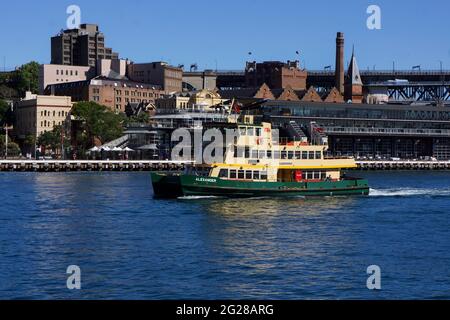 Die Fähre vom Hafen Sydney verlässt den Circular Quay und fährt am Passagierterminal in Übersee vorbei, im Hintergrund beginnt die Harbour Bridge Stockfoto