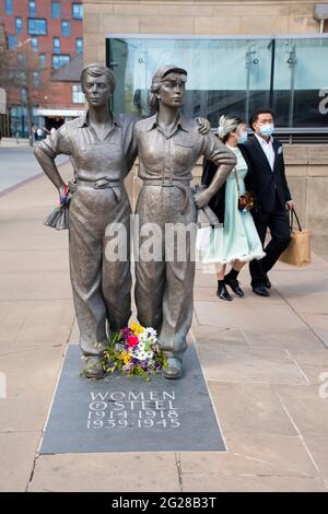 Sheffield UK: 17. April 2021: Die Statue von Women of Steel und ein vorbeigehende Paar, das Masken trägt, als Sheffield nach der Pandemie am Barkers Pool wieder aufmacht Stockfoto
