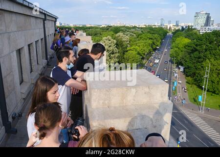Die Besucher besuchen die obere Terrasse des Triumphbogens mit Panoramablick auf die Stadt. Bukarest, Rumänien - 6. Juni 2021. Stockfoto