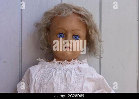 Gruselige, gruselige alte antike Puppe mit starrenden blauen Augen und Narbe und mit unordentlichen blonden Haaren für halloween Stockfoto