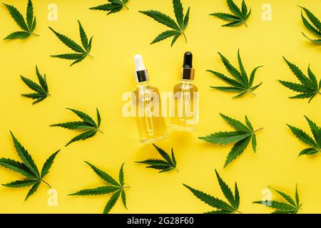 Hanföl-Serum in Glasflaschen mit Cannabisblättern. Cannabisblatt-Muster mit Kosmetikprodukt CBD-Öl auf gelbem Hintergrund mit Kopierraum Stockfoto