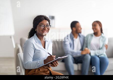 Glücklicher afroamerikanischer Psychologe und umarmtes Ehepaar im Büro nach erfolgreicher Therapie, Copy Space Stockfoto