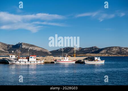 Griechenland. Koufonisi Island, Kykladen, 22. Mai 2021. Weiße Fischerboote am Dock festgemacht. Leuchtturm am Hafen an der Ägäis, blauer Himmel im Hintergrund. Sunny Sum Stockfoto