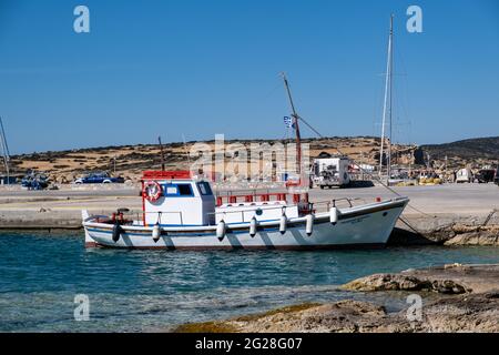 Griechenland. Koufonisi Island, Kykladen, 23. Mai 2021. Traditionelles Fischerboot aus Holz, das am Hafendock, blauem Meer und Himmel vor Anker liegt. Sonniger Sommer da Stockfoto