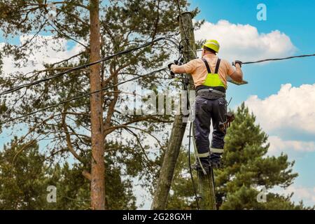 Elektrischer Lineman Verbindungsleitungen hoch auf elektrischen Pol. powerline Wartung und Reparatur Stockfoto