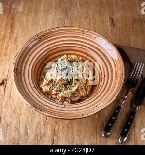 Pasta mit Hühnerfilet, Parmesankäse und Pilzen. Auf einer hölzernen Oberfläche. Traditionelles italienisches Gericht. Foto für das Menü. Stockfoto